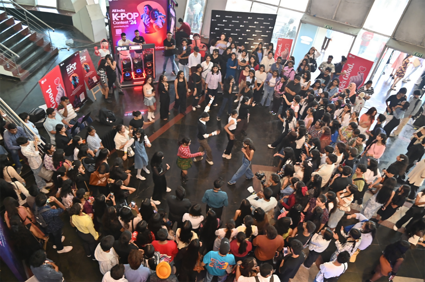 A photo taken from above of people dancing at the All India K-POP Contest and a large crowd of people watching the performance