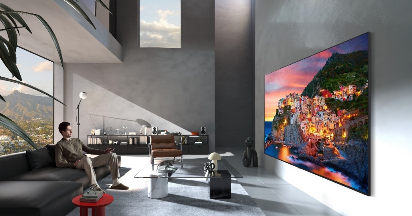 LG Micro RGB evo, designed with Flush-fit Design, is seamlessly wall-mounted in a spacious room, displaying a coastal village landscape in vivid colors that harmonize with the surrounding interior. 