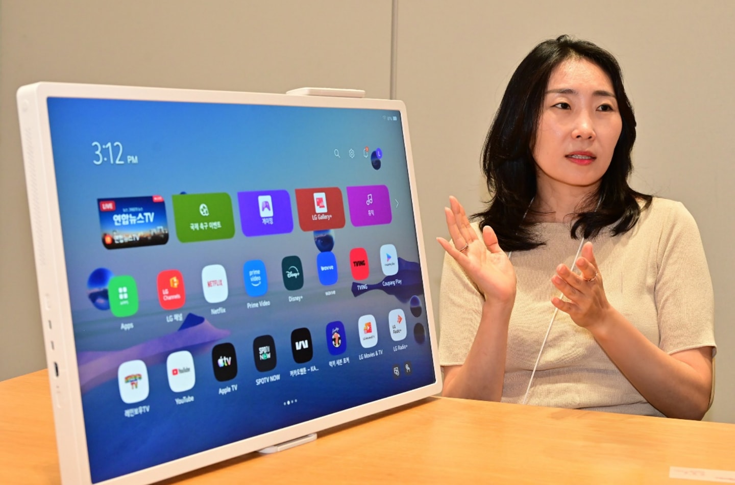 Shin Jina of LG Electronics discusses StanbyME’s webOS interface beside the display during an interview.