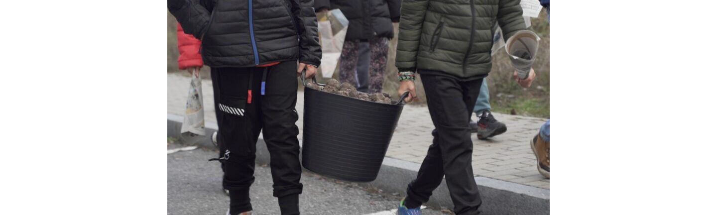 Children carrying a large bucket of seed balls they made with the help of LG employees.