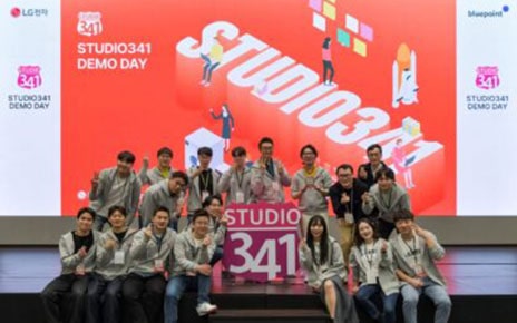 A photo of people sitting, smiling, and posing together on stage at a demo day event of STUDIO341 
