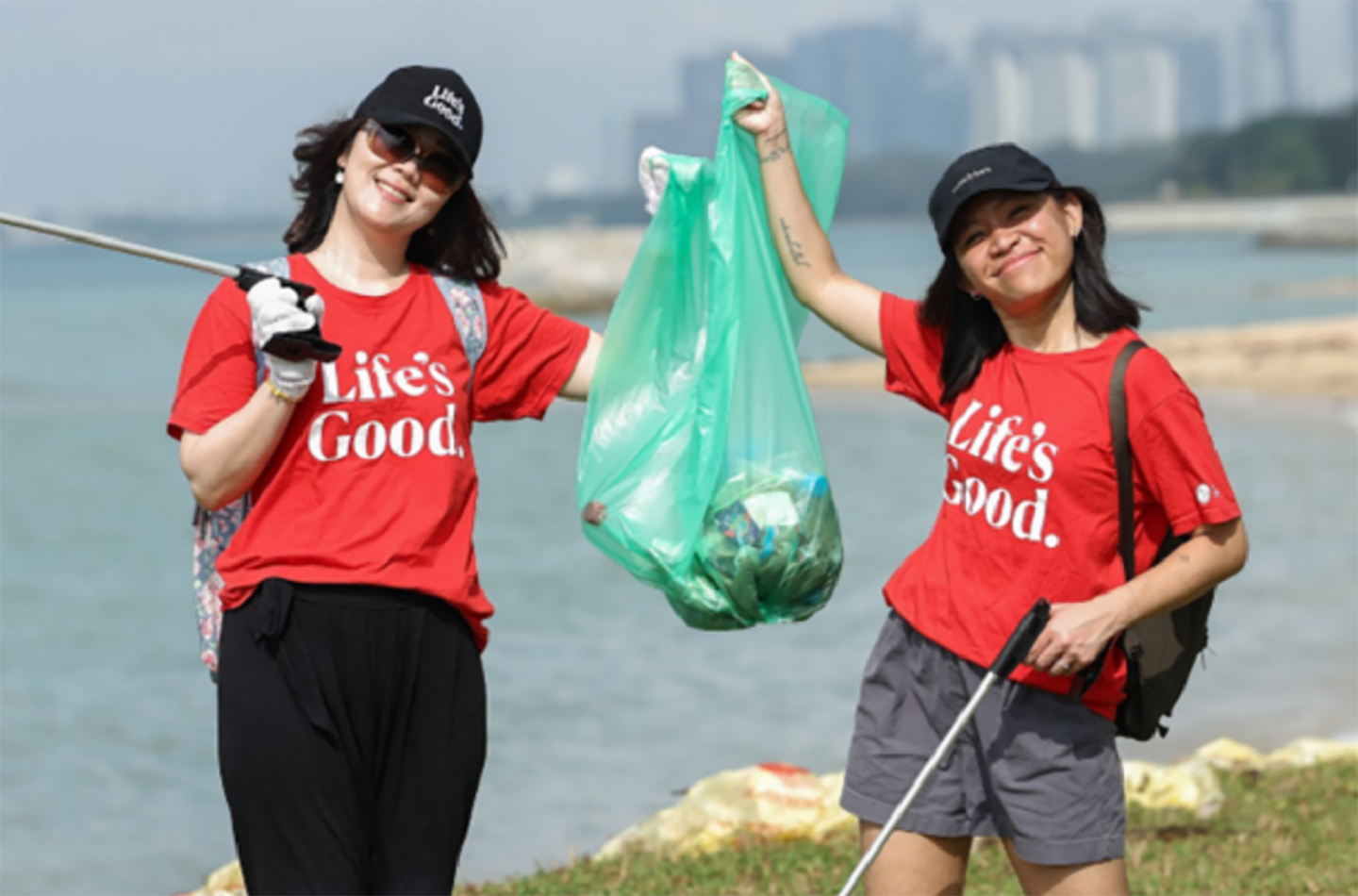 A picture of two LG Singapore employees holding up trash at the ocean