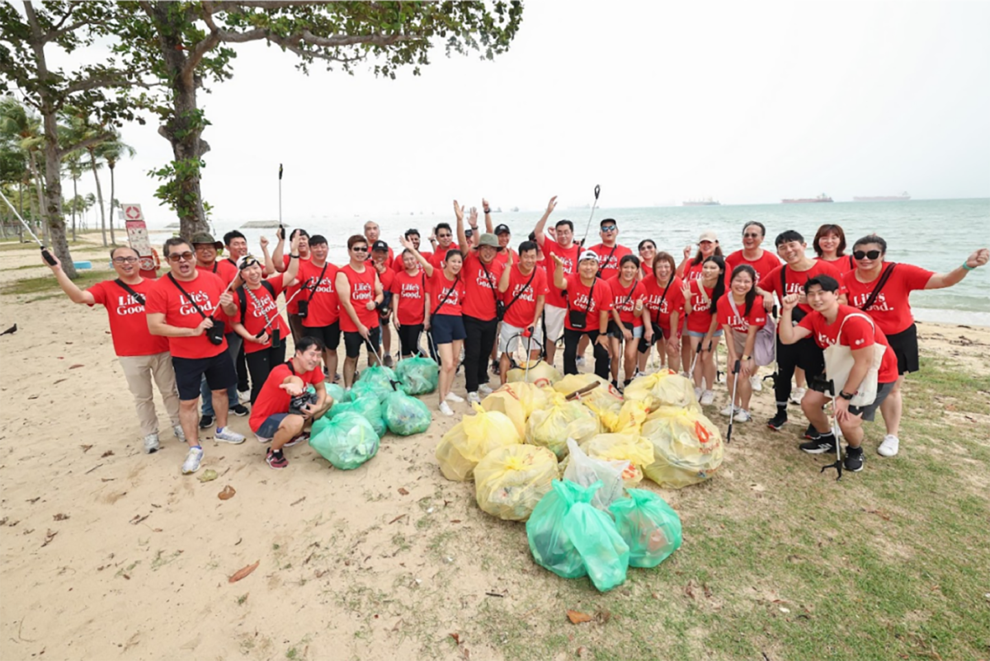 A group picture of LG Singapore employees gathered around the trash they collected from the ocean