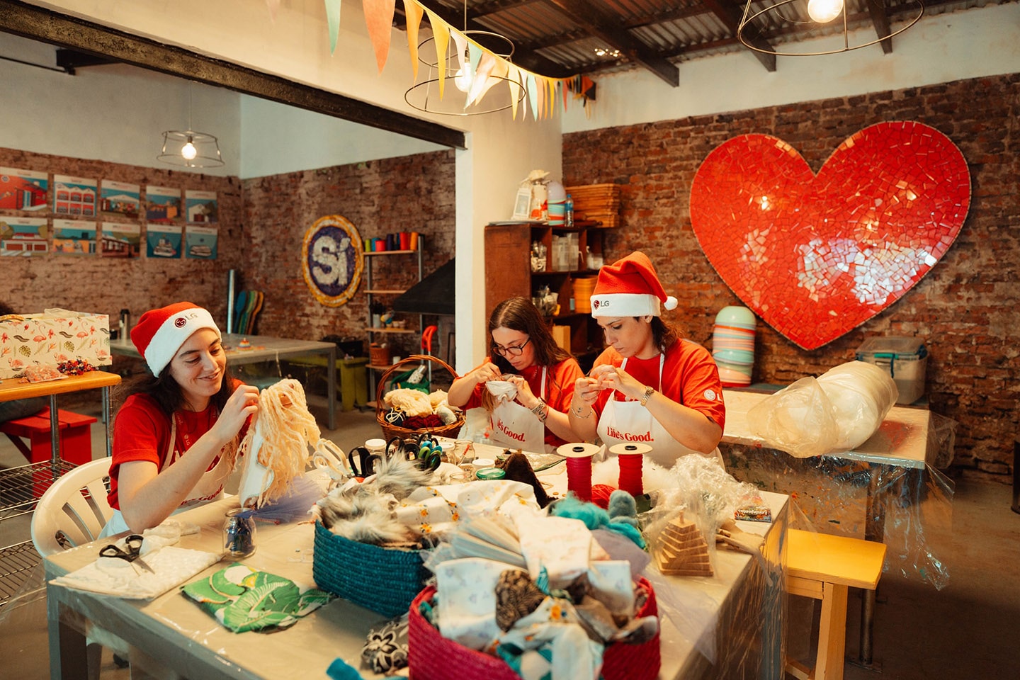 A photo of three LG employees in Santa Claus hats making hand-painted toys