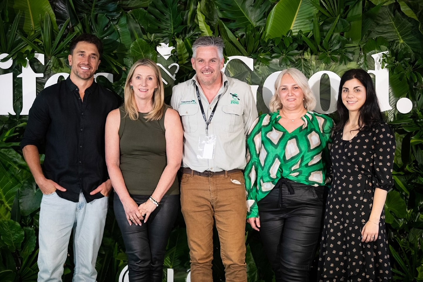 A photo of five people smiling in front of a wall of Life's Good logos