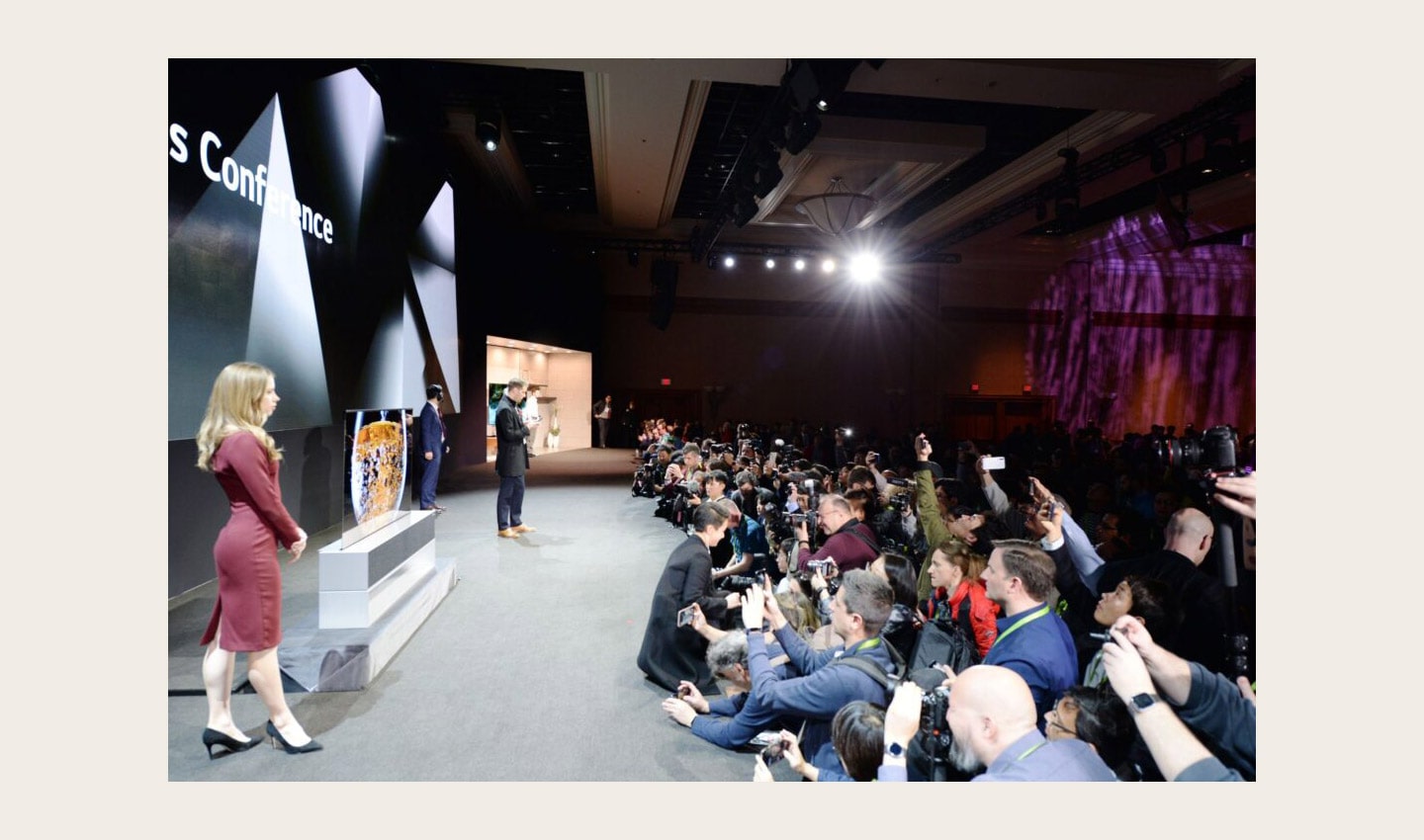 Side view of the CES 2019 LG Press Conference with a pair of male and female models onstage posing while reporters are recording and taking pictures
