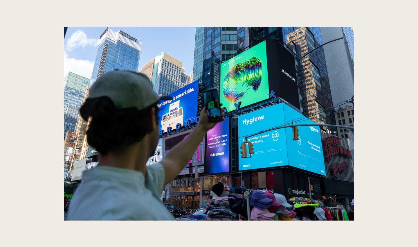 A passerby taking a picture of LG's massive, high-definition digital billboard in Time Square, New York displaying the artwork of David McLeod
