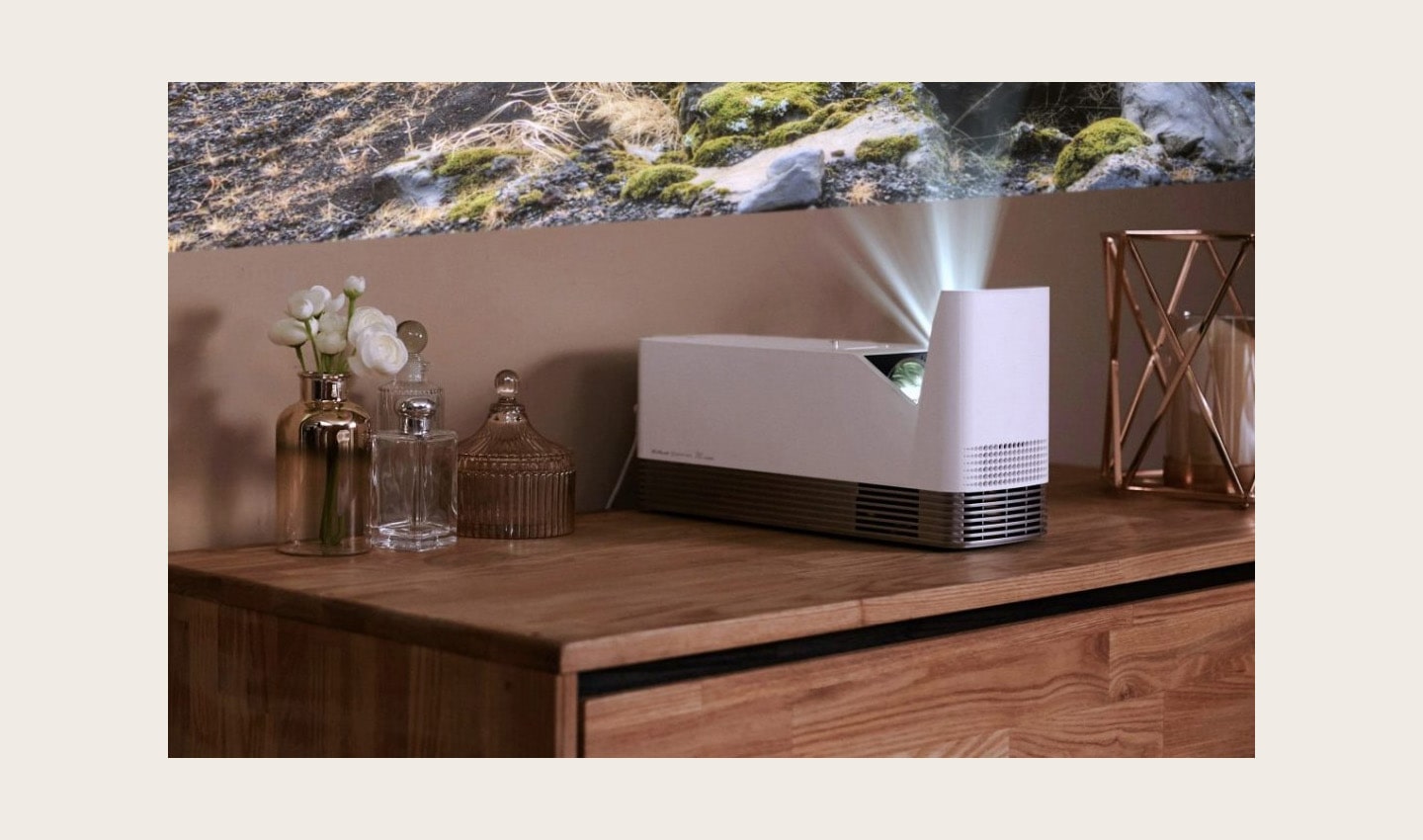 An LG ProBeam Projector HF85J is put next to some perfumes on a cabinet, projecting an image on the wall.
