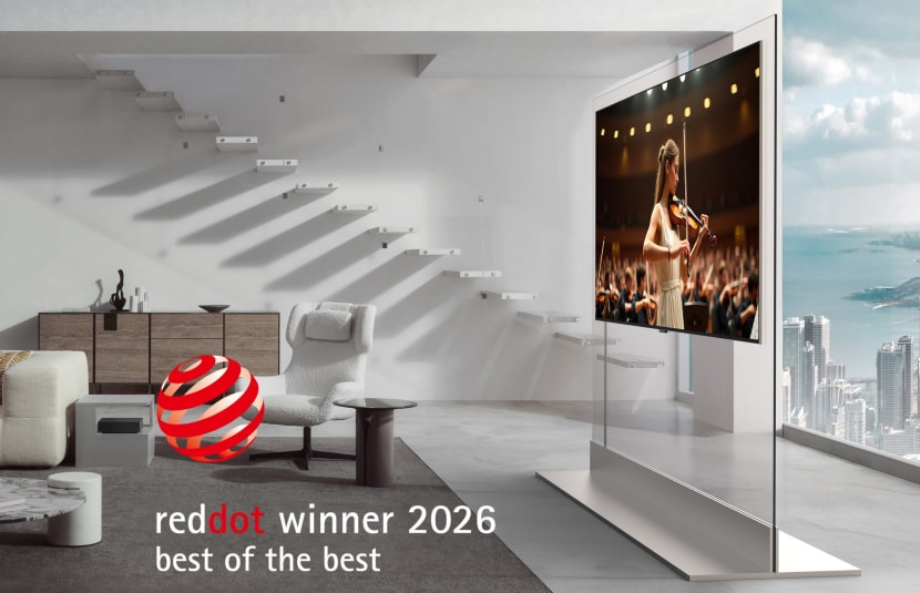 An LG OLED evo W6 Wallpaper TV displaying a violin performance is attached to a transparent stand, with a "Red Dot Winner 2026 Best of the Best" graphic in the corner.
