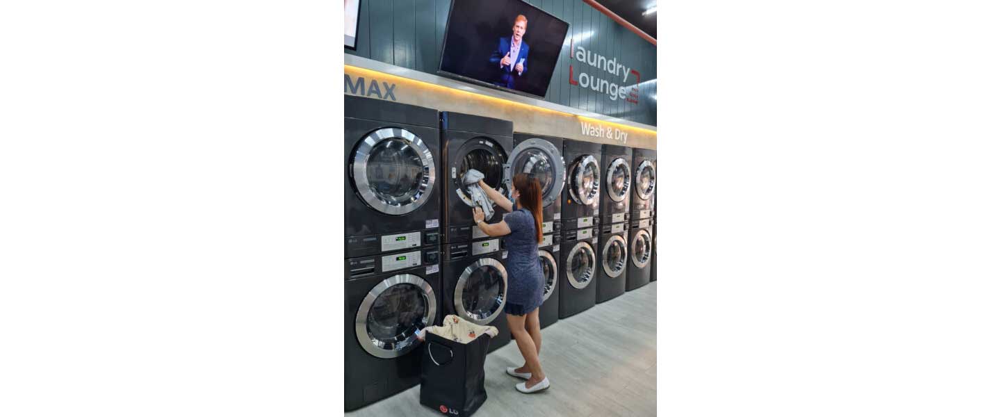 A woman is putting laundry into dryer at Laundry Lounge.