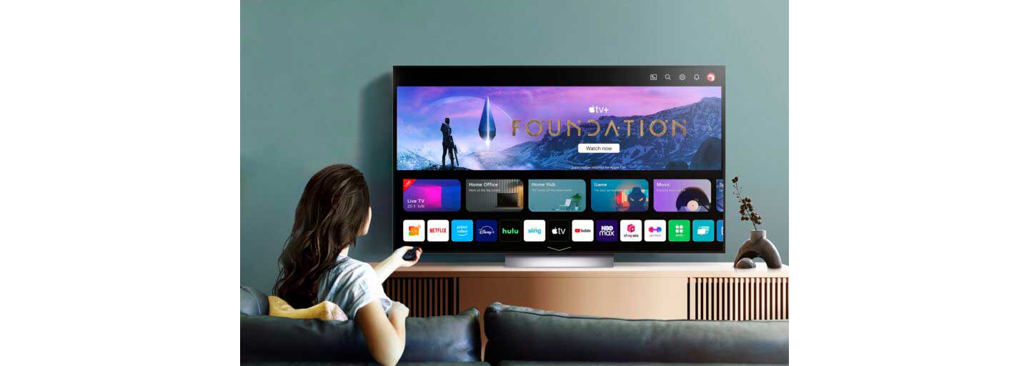 A woman scrolling through the various applications available on the 2023 LG OLED TV, including Apple TV+ which comes free