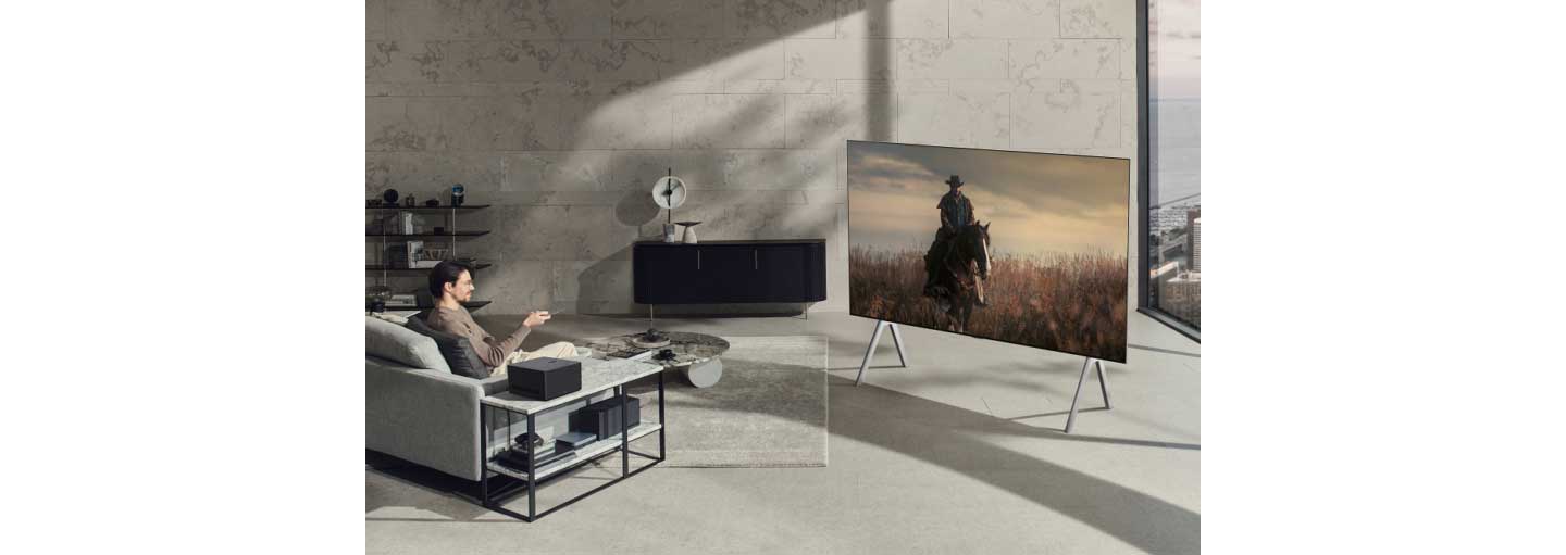 A man watching a TV series on the new LG OLED M3 while sitting on his living room sofa