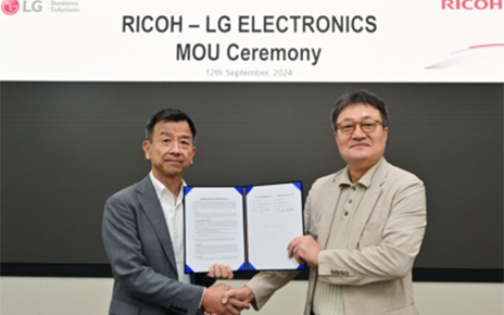 Representatives from LG (left) and Ricoh (right) shake hands while holding a signed MOU