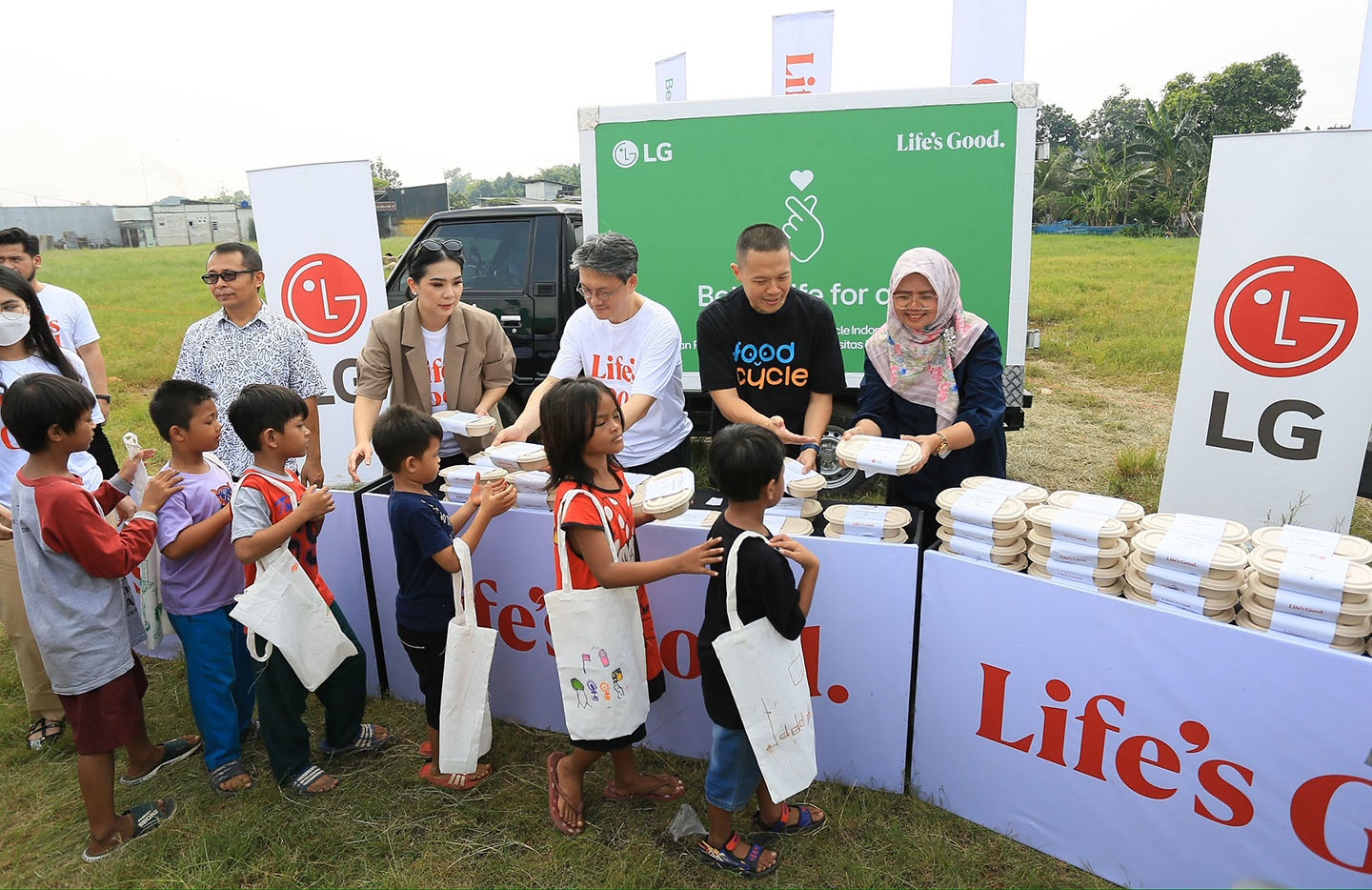 A photo of people handing out to children waste-free meal kits at a food donation event