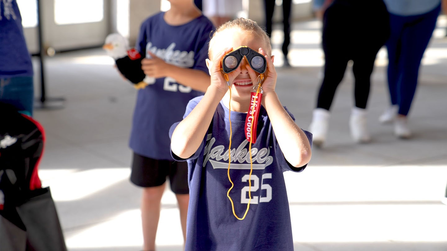 A picture of a young boy looking at the camera through a telescope