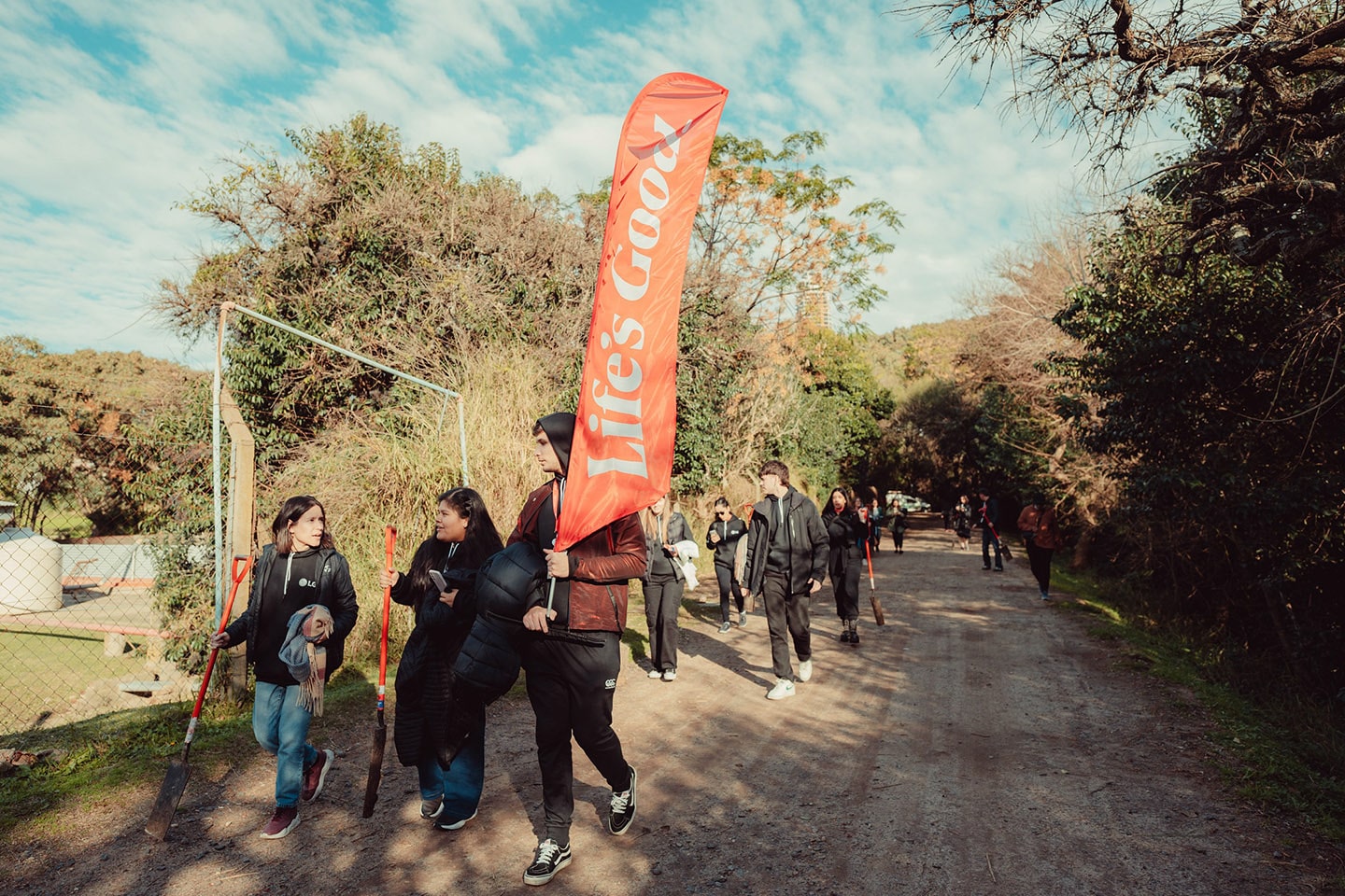 A picture of LG Argentina volunteers walking through a park holding a Life's Good sign