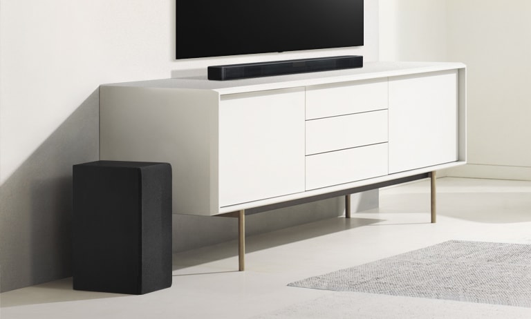 Sound Bar 置於白色層架上，左面是重低音喇叭。重低音喇叭較前，所以顯得較大。