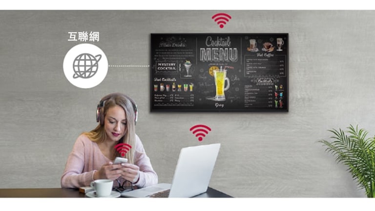 牆上掛著 UR3J 系列，一位女士正在使用個人電腦和手機。這張圖顯示標示可以無線連接到她所持有的電腦和手機。