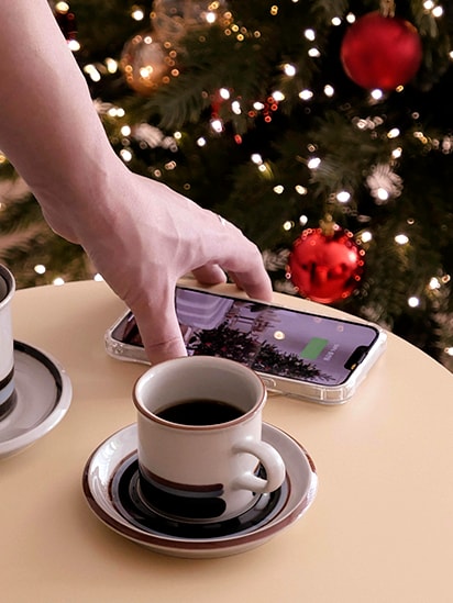 手機放於產品頂部，能夠充電。旁邊放有咖啡杯，顯示產品用作桌子。