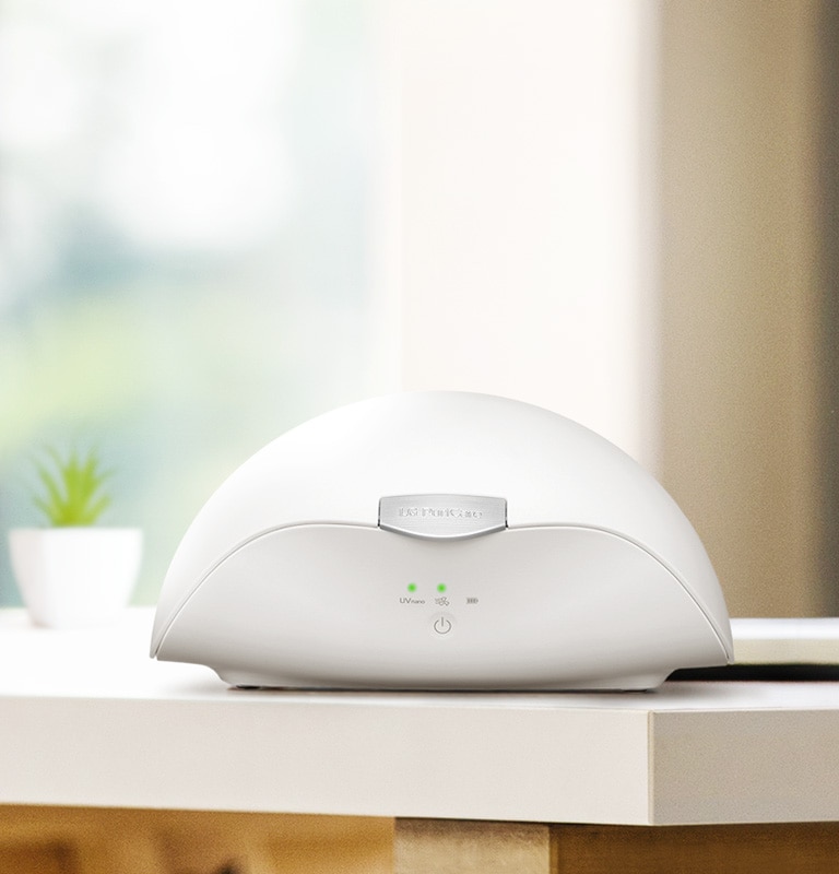 穿戴式空氣清新機機盒放在桌子中央。左側的兩個 LED 狀態燈亮著。
