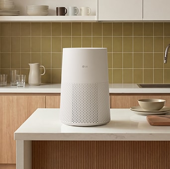 白色 LG AeroMini 空氣清新機放在乾淨的白色廚房台面上，背面有瓷磚牆面。