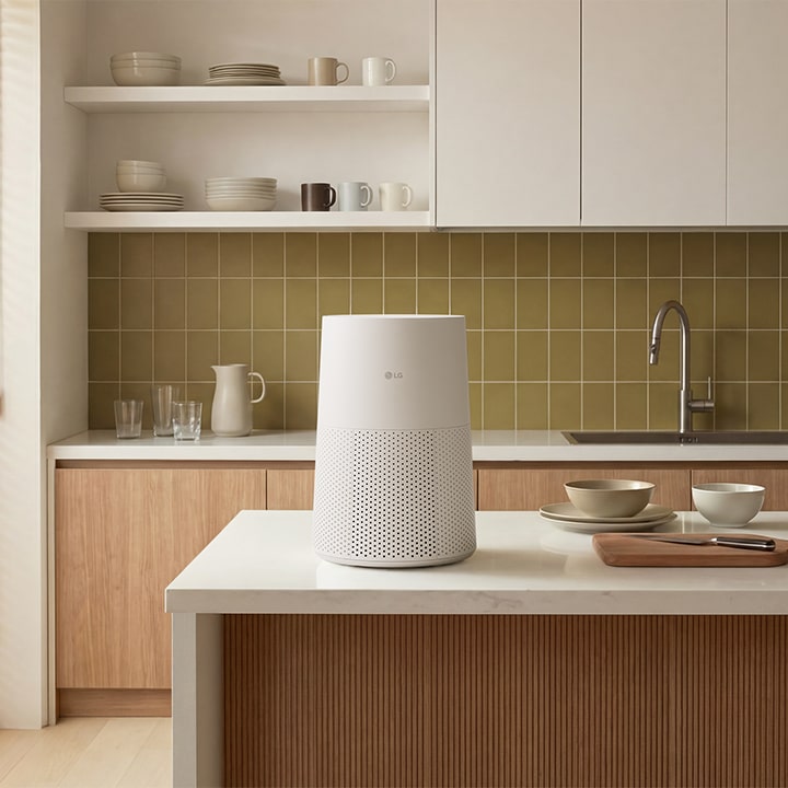 白色 LG AeroMini 空氣清新機放在乾淨的白色廚房台面上，背面有瓷磚牆面。