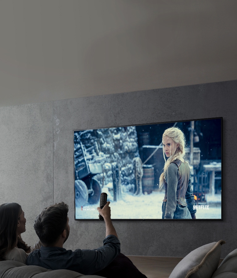 影像顯示一對夫妻使用 LG 超高清電視觀賞節目。