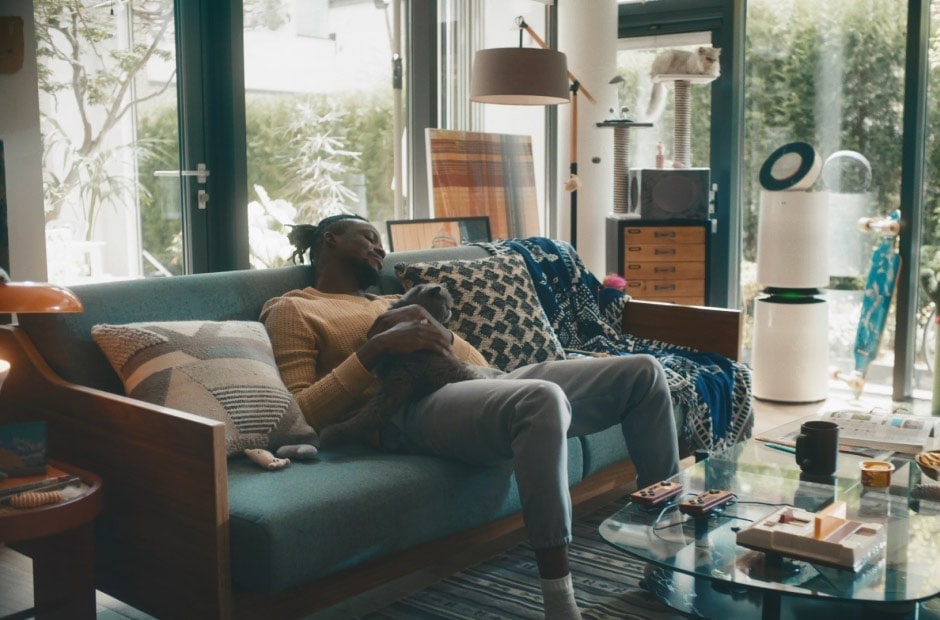 影片顯示一名男子在客廳和他的貓玩耍。他在 LG ThinQ 應用程式上打開了預設的例行模式，以啟動空調和空氣清淨機。