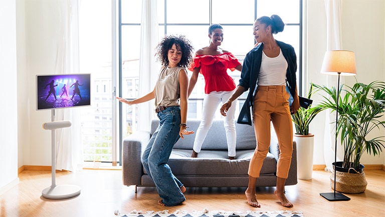 The LG StanbyME is placed in the living room with the LG StanbyME Speaker XT7S attached. People enjoy the music with the screen and speaker combo.