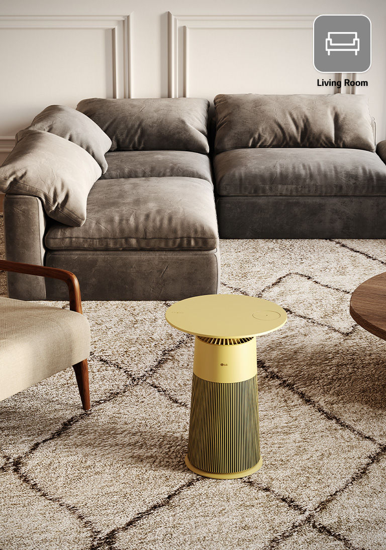Yellow LG PuriCare air purifier in a living room with a grey sectional sofa and beige armchair on a textured rug.