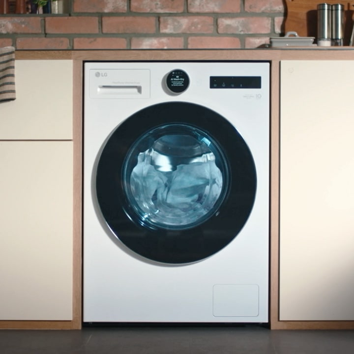 LG white washer dryer fitted snugly into the center of beige cabinetry