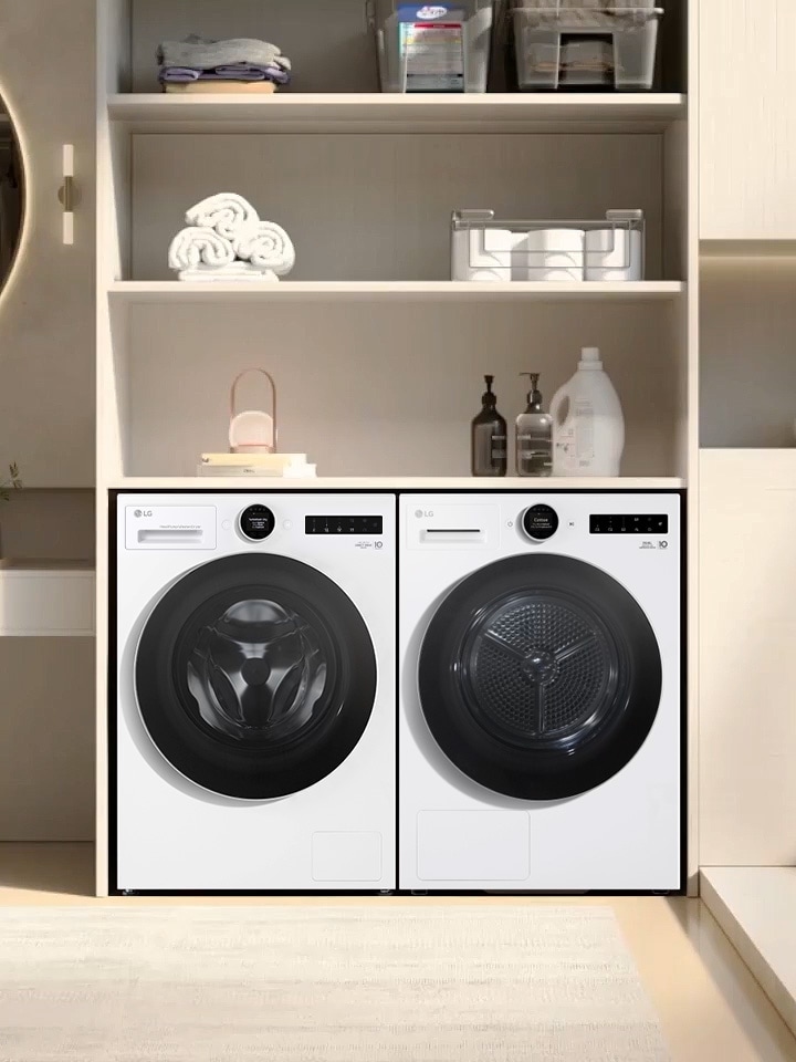 LG white front load washer dryer is placed beside a matching dryer under shelves stocked with laundry supplies.