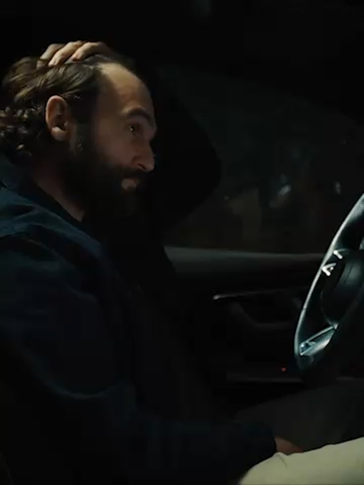 Inside a car with two people sitting, the LG AI logo is glowing on the screen.