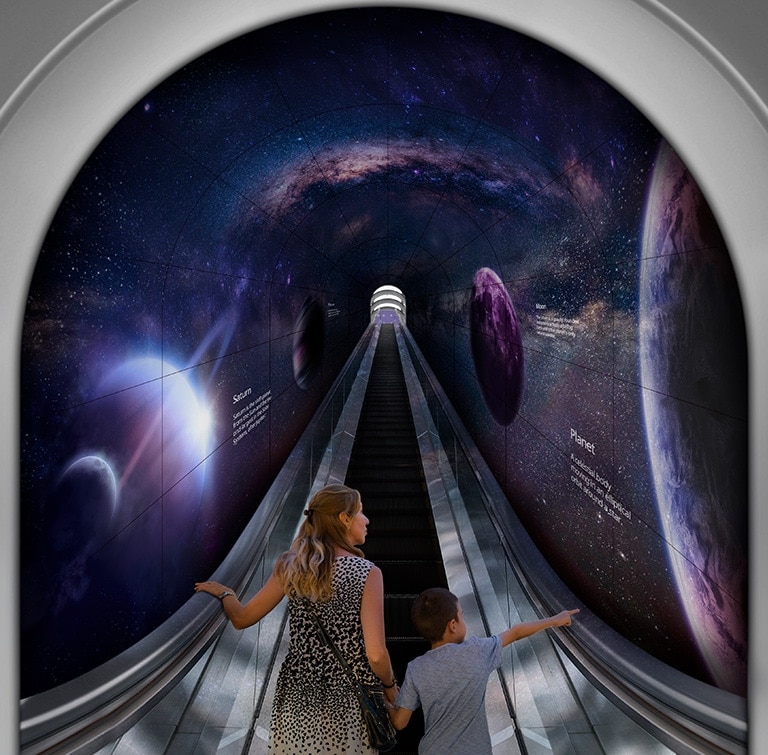 A woman and a child are going up a tunnel made of flexible Curved Open Frame OLED Signage through an escalator.