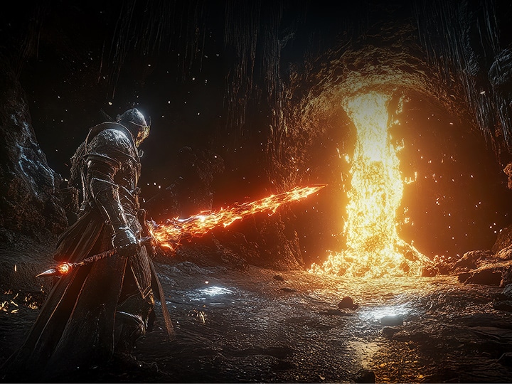 A knight in armor rides a horse through a lush forest path, with tall grass and ancient stone ruins visible in the misty background. Scene from the game Elden Ring by Bandai Namco Entertainment and FromSoftware.