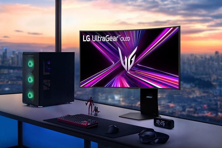 LG UltraGear OLED monitor on a gaming desk with a PC setup, overlooking a cityscape at sunset.