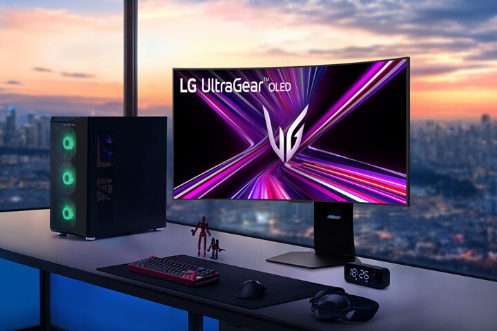LG UltraGear OLED monitor on a gaming desk with a PC setup, overlooking a cityscape at sunset.