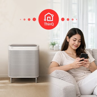 A woman using her smartphone to control an LG air purifier remotely via the ThinQ app.