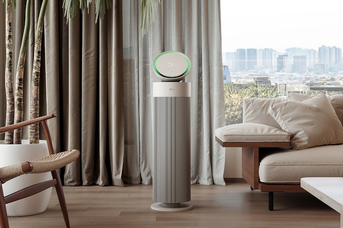 LG air purifier placed in a stylish living room with a beige sofa, dark bookshelf, and modern décor