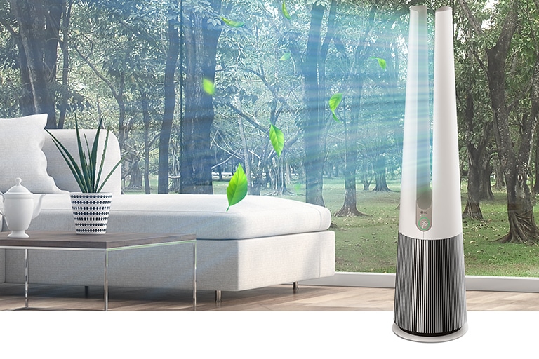 LG air purifier standing near a modern white sofa with large windows showcasing a lush green forest in the background.