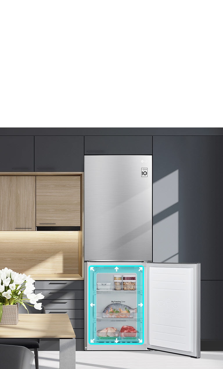 LG refrigerator in a modern kitchen, freezer door open showing organized food, vase of white flowers on table beside it.