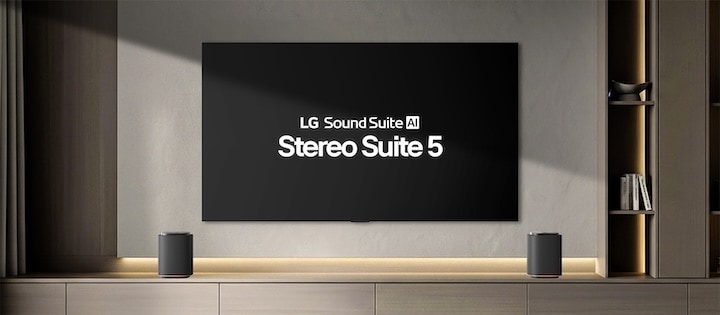 A Sound Suite M5 speaker set is placed on stands in front of a TV mounted on a gray-toned wall.
