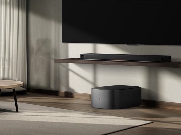 LG Sound Suite W7 woofer placed below a TV with a soundbar, showing easy wireless sound expansion for an immersive home stereo audio system