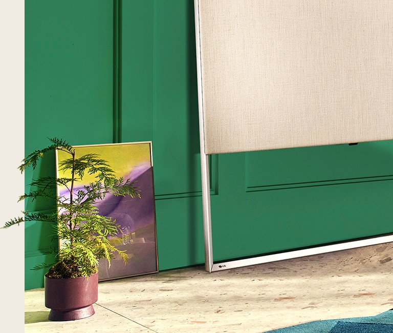 Close-up of Easel on the floor leaning against the wall together with a painting and decorative plant.