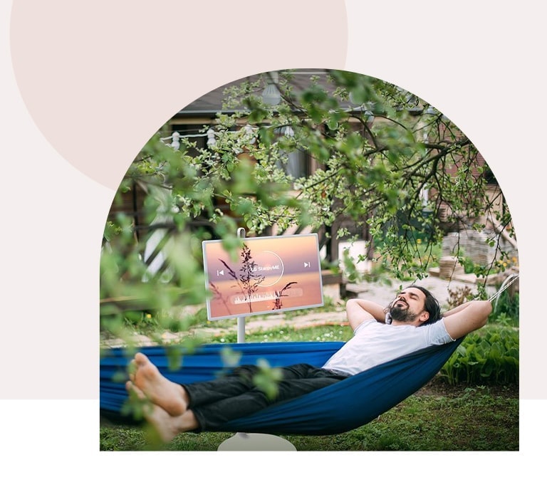 TV is placed in front of hammock in terrace. The image is cropped in arch-shape.