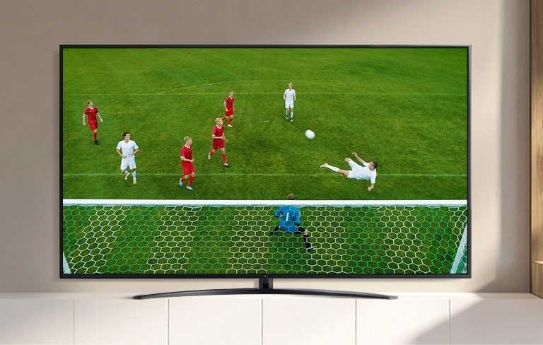 A TV screen playing a video of a soccer player making a goal during a soccer game. (play the video)