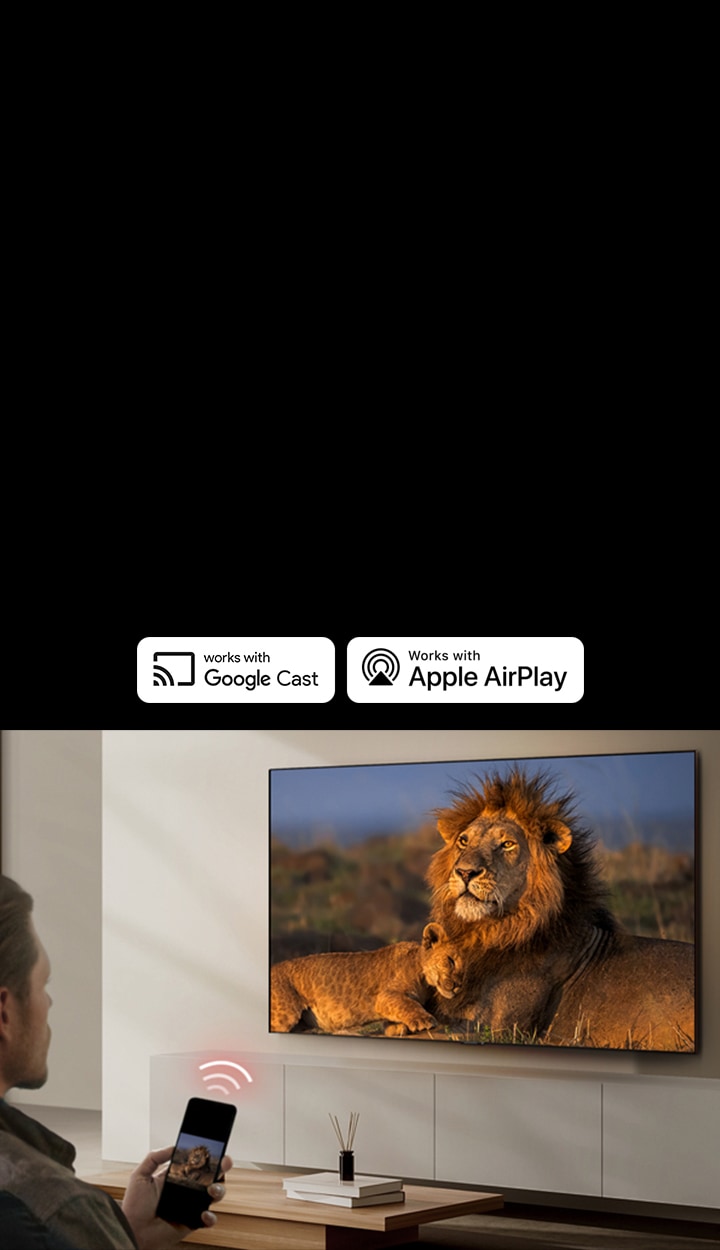 An LG TV mounted on a wall in a living room, displaying a lion and lion cub. A man sits in the foreground with a smartphone in his hand displaying the same image of lions. A graphic of three neon red curved bars is displayed just above the smartphone pointing toward the TV.