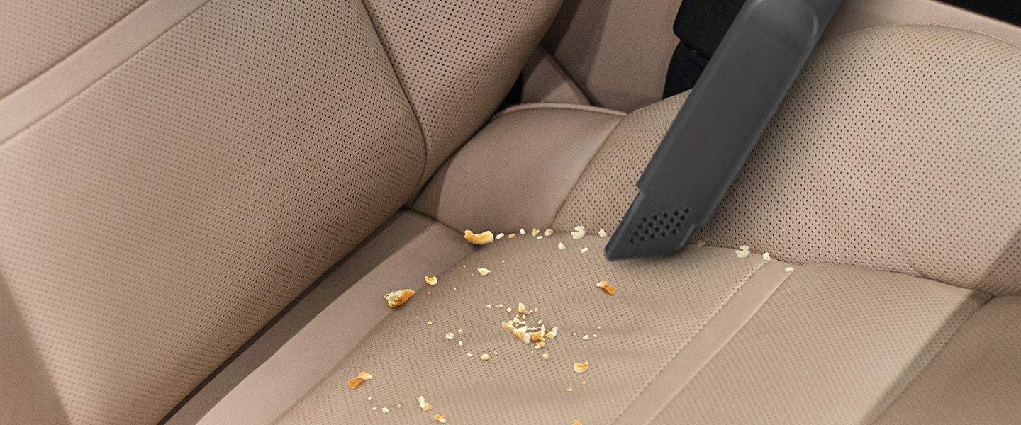 This image shows you cleaning the car seat with a Crevice Tool.