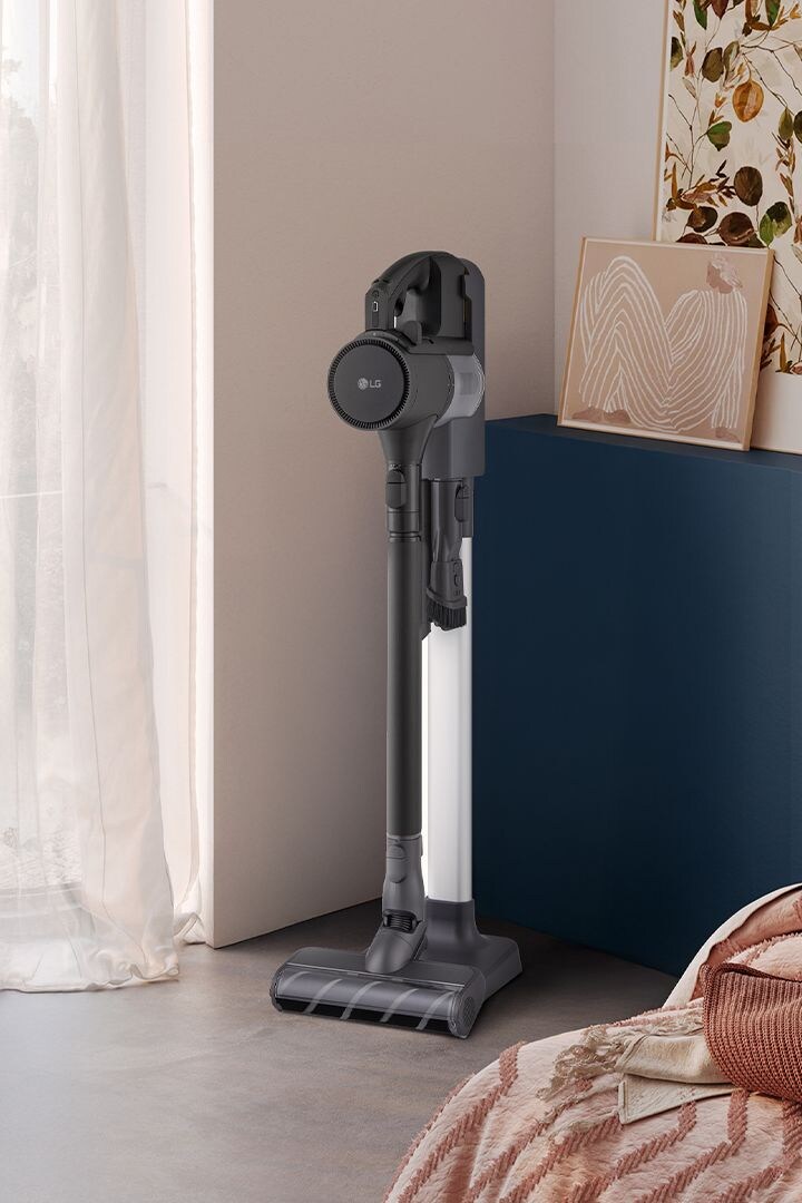The LG vacuum is neatly docked in a stylish bedroom corner, blending seamlessly with modern interior decor.