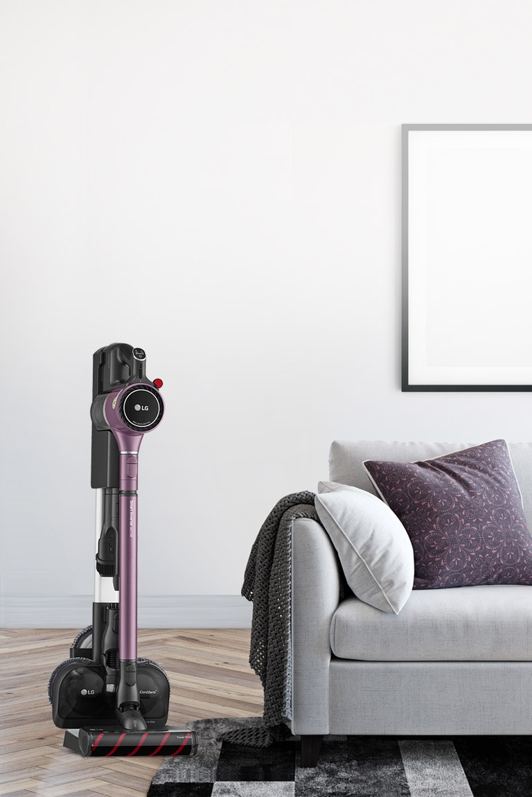 The CordZero A9 Kompressor Vacuum is in the charging stand in a bedroom next to a bed.